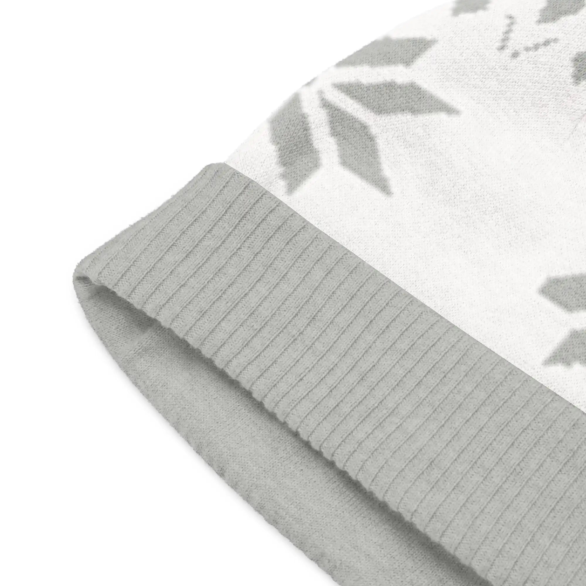 AEMBR knitted beanie close-up, light gray with ribbed cuff and subtle snowflake pattern