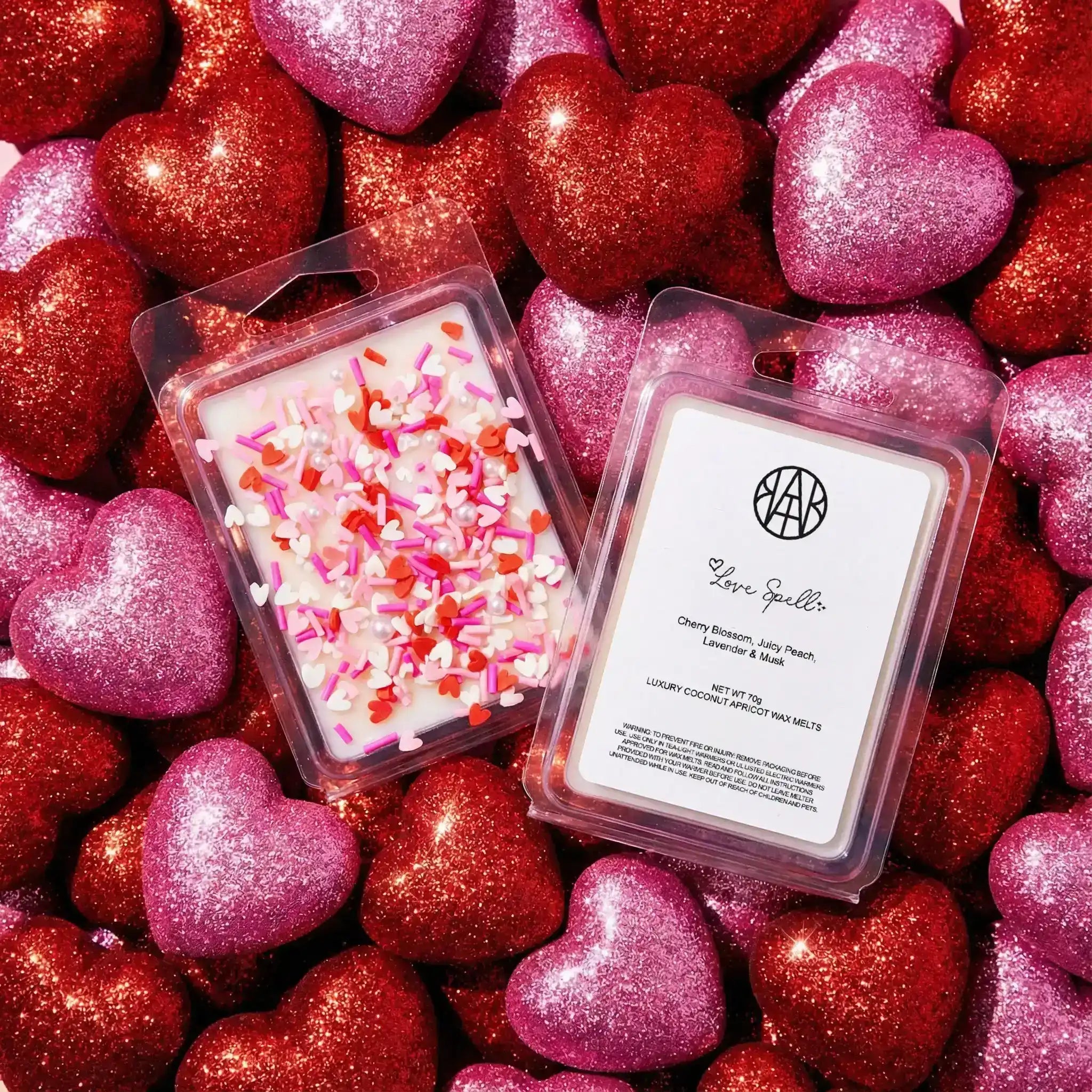 AEMBR Love Spell wax melts with heart sprinkles on glittery red and pink heart background
