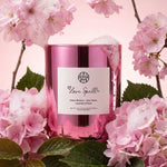 AEMBR Love Spell pink candle surrounded by cherry blossoms and peonies, non-toxic home fragrance