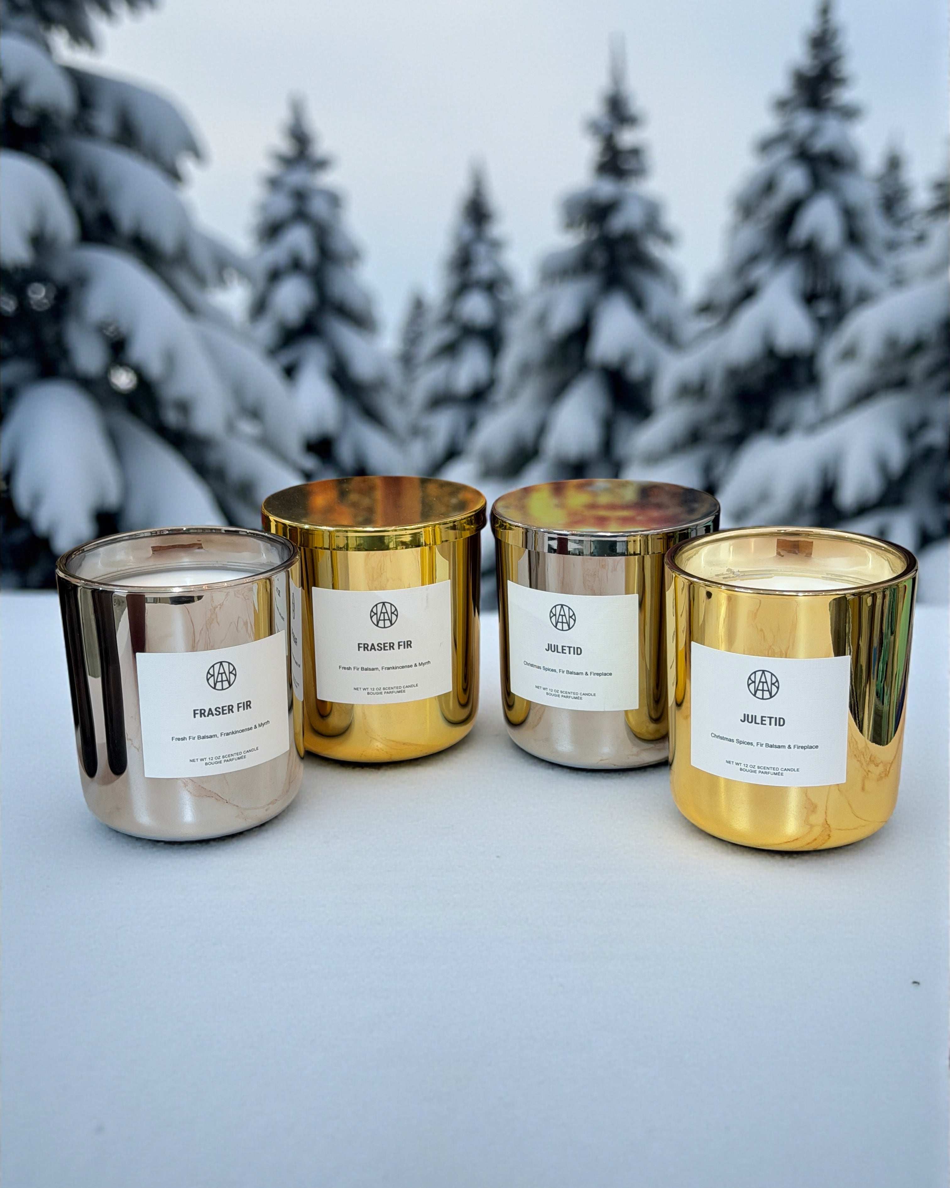 Set of five candles with gold and silver finishes on a snowy surface with trees in the background.