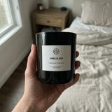 woman's hand holding aembr vanilla ash candle in her bedroom