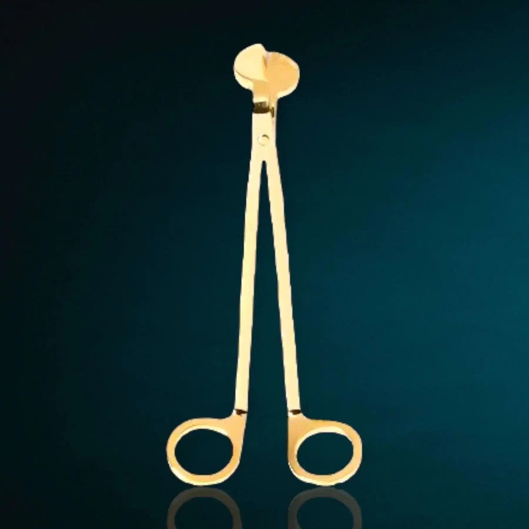 Gold wick trimmer by AEMBR for candles, displayed on a dark background