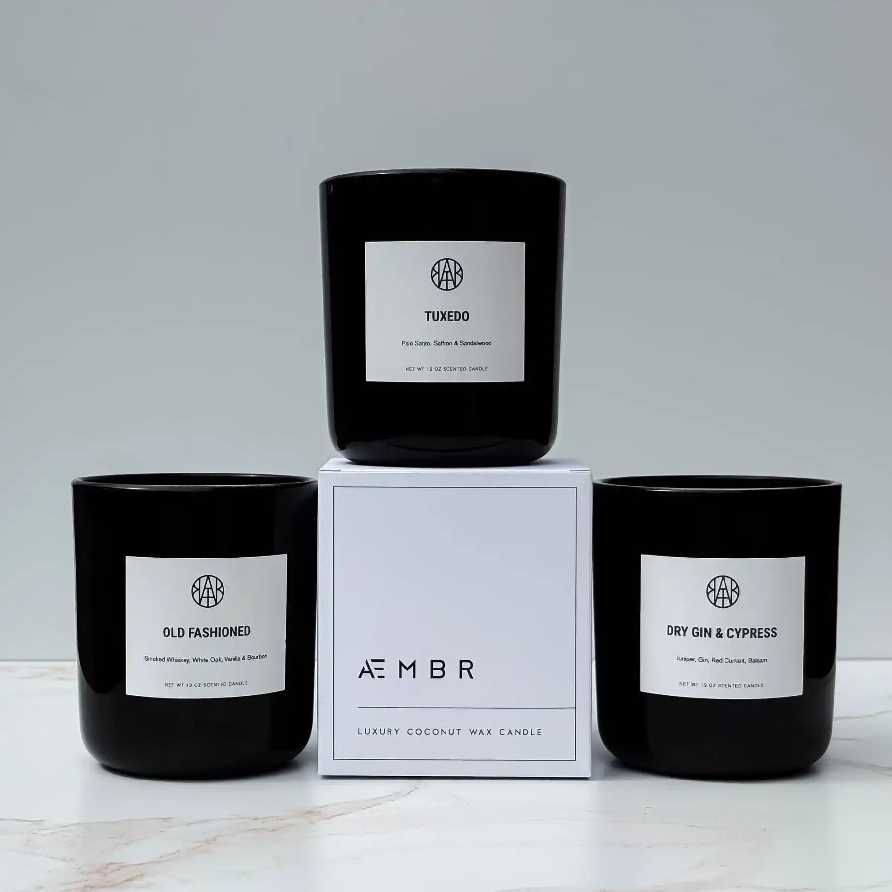 AEMBR luxury coconut wax candles in black glass jars with minimalist white labels, displayed on a white surface.