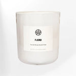 AEMBR Fjord candle with sea salt, blonde woods, and sage in a minimal white glass jar