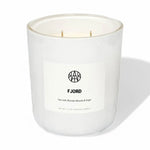AEMBR Fjord scented candle in white glass jar with sea salt, blonde woods, and sage label.