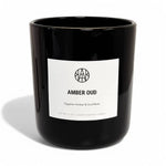 AEMBR Amber Oud scented candle in sleek black glass jar with minimalist white label.