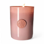 AEMBR non-toxic wooden wick candle in pink glass jar, lit against a white background
